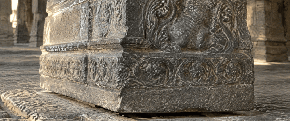 Low-angle view of granite pillars and ceiling beams showing how weight is carried in a stone temple